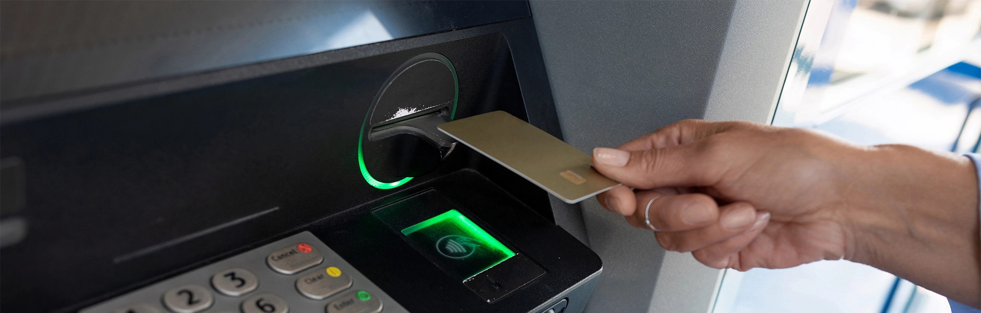 a female hand applies a bank card to an ATM